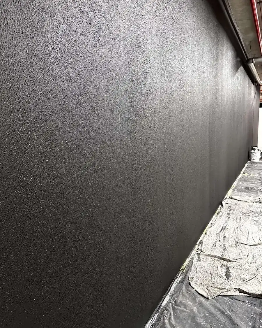 Large charcoal textured wall with floor protection in place